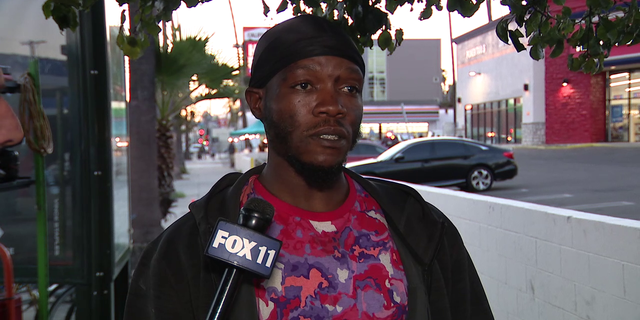 A homeless man who calls himself "Q" speaks to local media asking about a small wooden home he constructed on a sidewalk. 