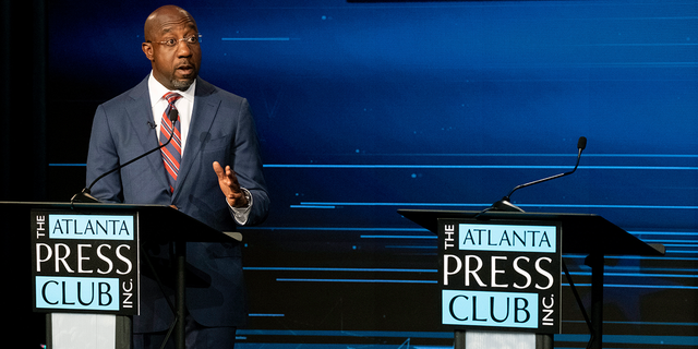 Sen.  Raphael Warnock, D-Ga., speaks next to an empty podium set up for Republican challenger Herschel Walker, who was invited but did not attend, during a US Senate debate as part of the Atlanta Press Club Loudermilk-Young Debate Series in Atlanta on Sunday, Oct. 16, 2022.