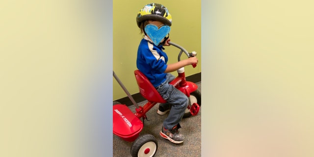 A One Simple Wish recipient (his face is covered for privacy) enjoys a brand new tricycle.