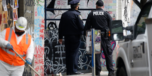 A worker sweeps the sidewalk as Seattle Police inspect the exterior of the department's East Precinct after police cleared the Capitol Hill Occupied Protest and retook precinct in Seattle on July 1, 2020.