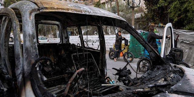 Palestinians look at a damaged car following clashes between Israel army and Palestinians during an Israeli raid in the occupied West Bank city of Nablus, Tuesday, Oct. 25, 2022. The military says Israeli forces have raided a stronghold of an armed group in the West Bank, blowing up an explosives lab and engaging in a firefight. Palestinian health officials say five Palestinians were killed and 20 were wounded. The target of the raid was a group calling itself the Lions' Den, accused by Israel of having killed a soldier and attempting several attacks.
