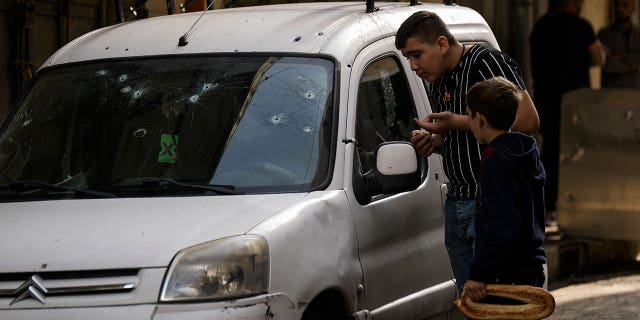 Palestinian kids look at a damaged car following an Israeli raid in the occupied West Bank city of Nablus, Tuesday, Oct. 25, 2022. The military says Israeli forces have raided a stronghold of an armed group in the West Bank, blowing up an explosives lab and engaging in a firefight. Palestinian health officials say five Palestinians were killed and 20 were wounded. The target of the raid was a group calling itself the Lions' Den, accused by Israel of having killed a soldier and attempting several attacks.