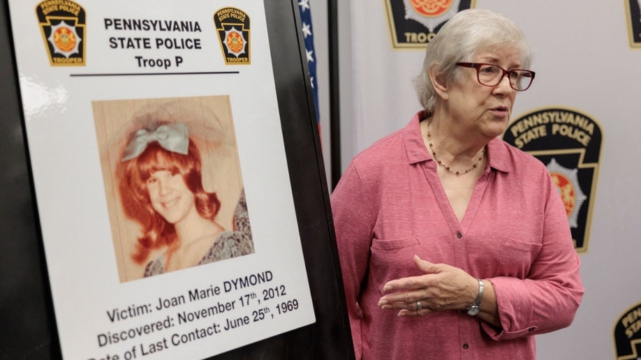 Suzanne Estock stands next to a photo of her sister, Joan Marie Dymond