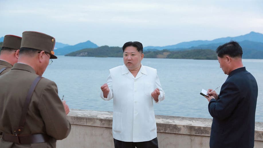 Kim Jong Un wearing a white button down and black pants while speaking to military personnel