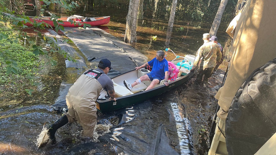 rescuers evacuating woman in boat
