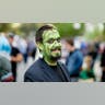 Man wears green Frankenstein face paint for Halloween