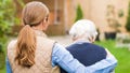 Young carer walking with the elderly woman in the park