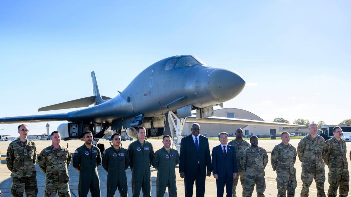 Air Force members stand in front of a B-1 bomber