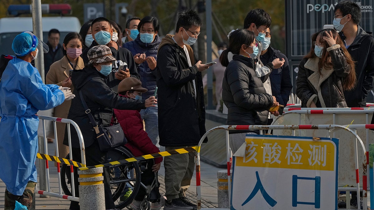 Chinese people on their smartphone in line for health check