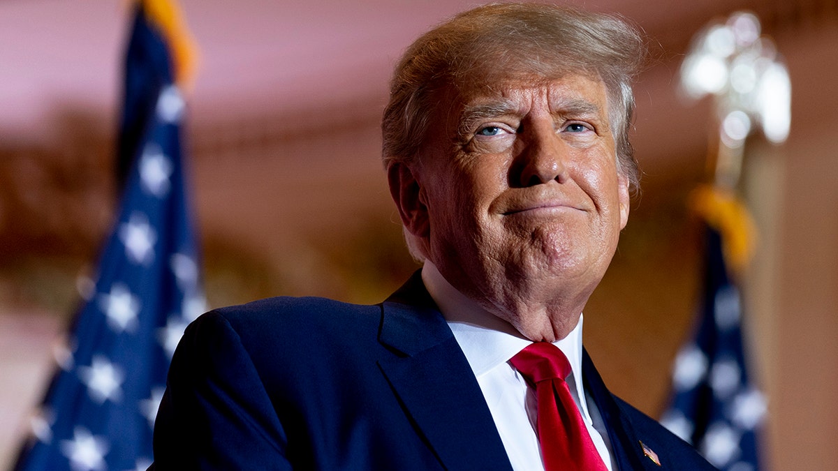 Donald Trump in red tie, US flags in background