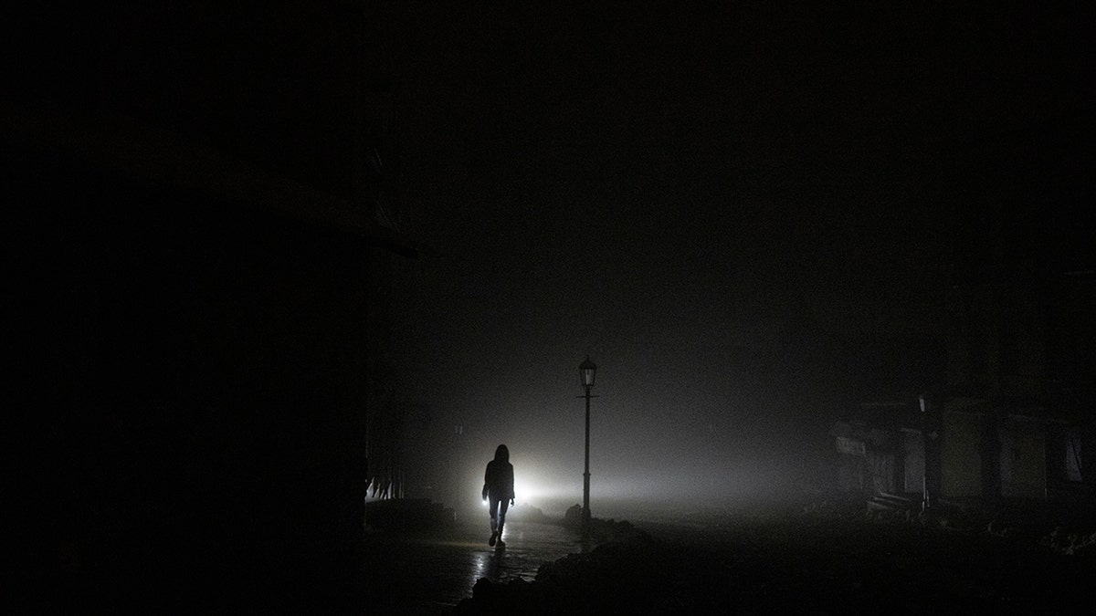 A woman walking in near complete darkness