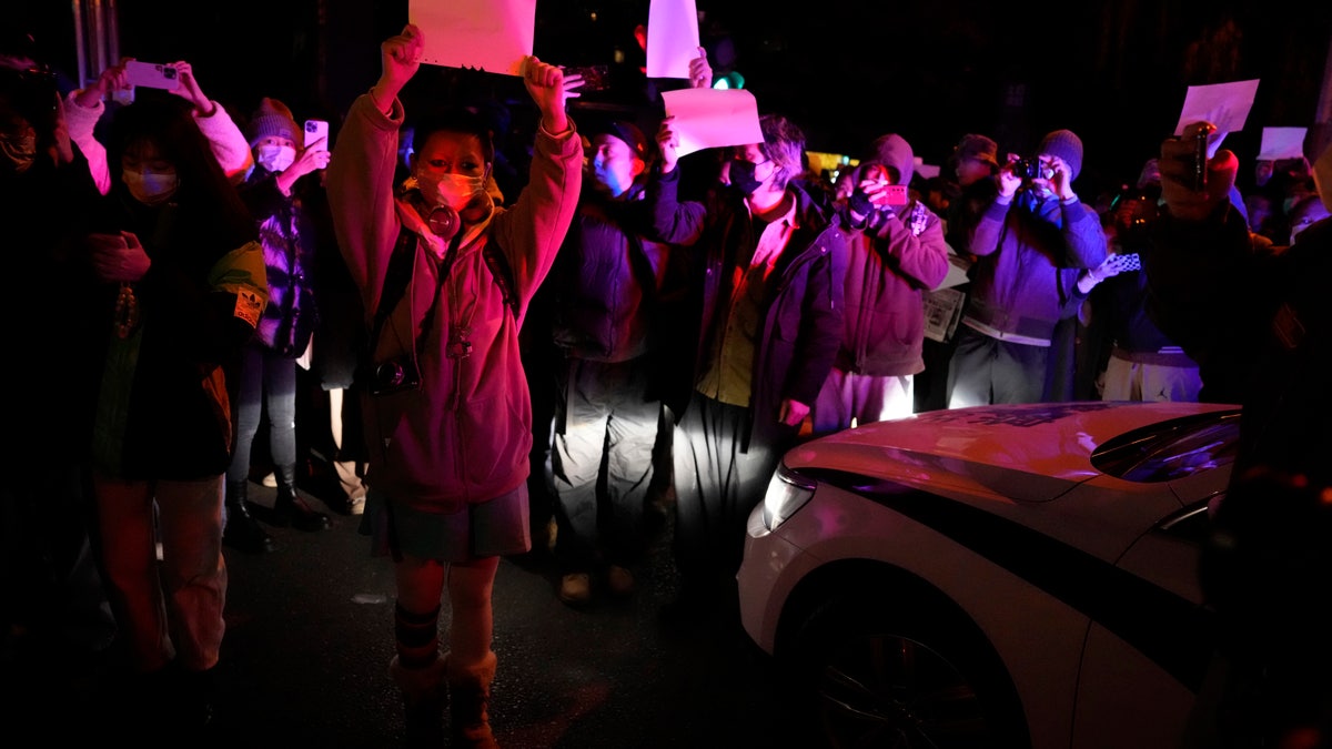 Protesters in China hold up signs in front of police