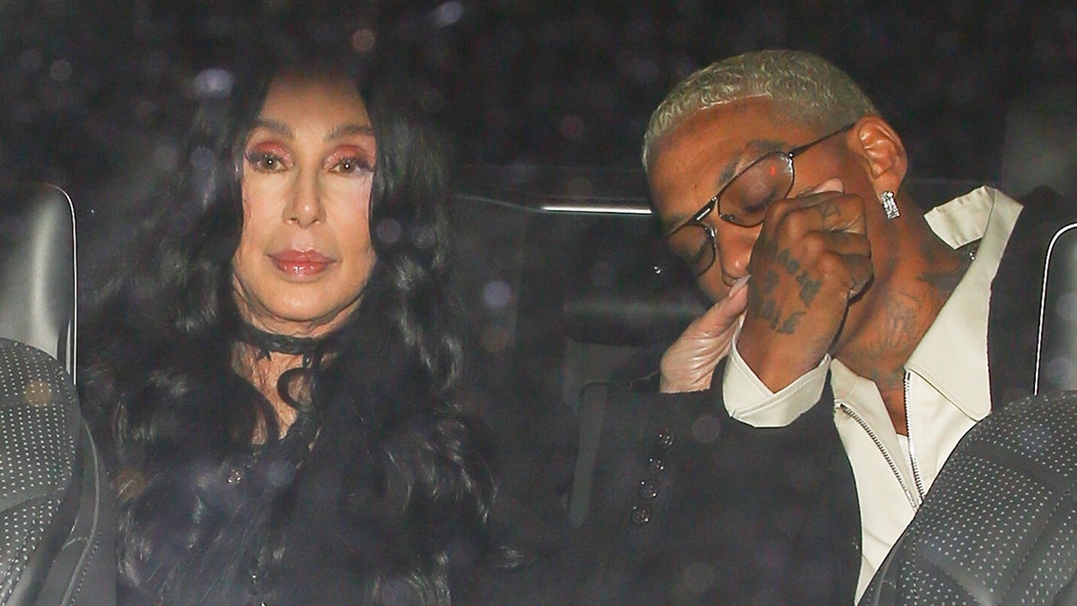 Cher sits in the back of her car and has her hand kissed by boyfriend Alexander Edwards