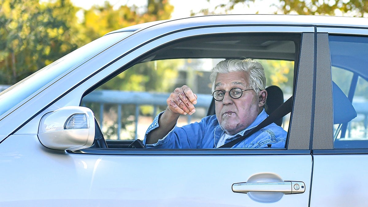 Jay Leno wears denim shirt while driving after being released from hospital