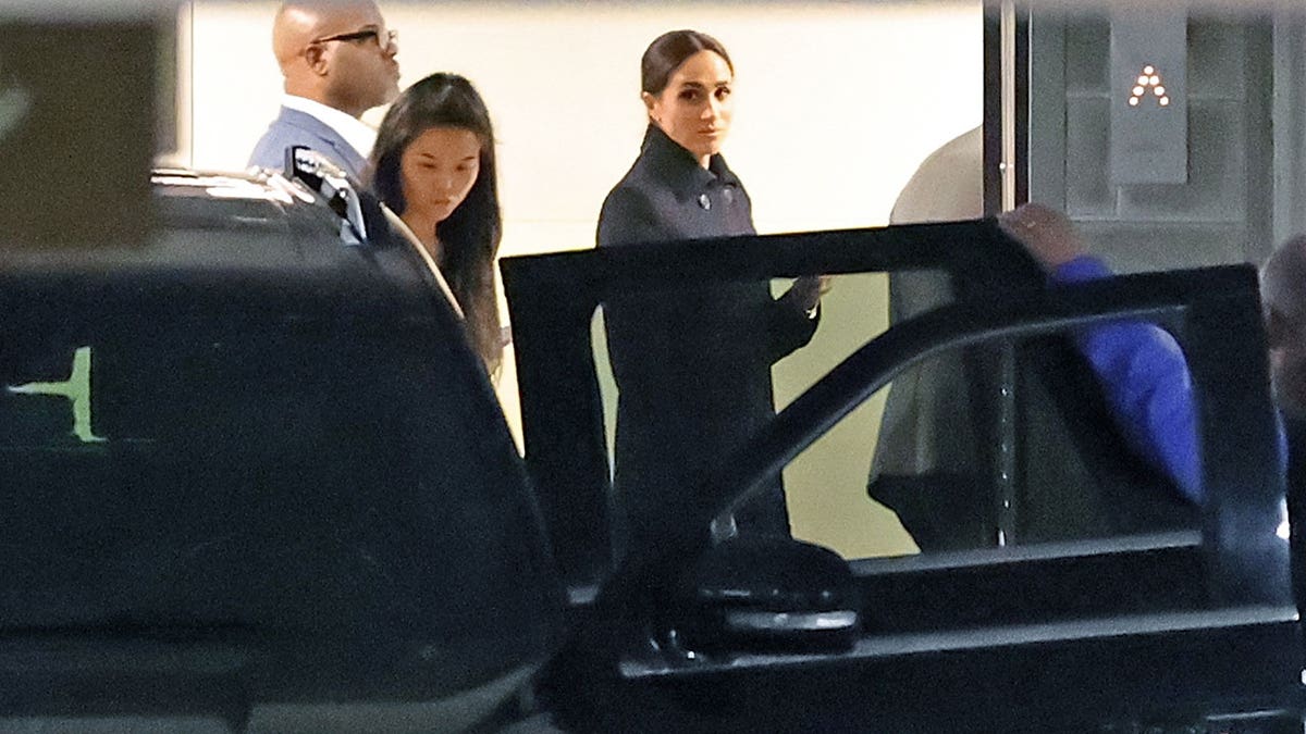 Meghan Markle looks toward the camera as she walks out of the car