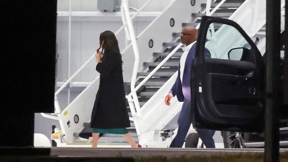 Meghan Markle walks towards plane hanger, her hair is down