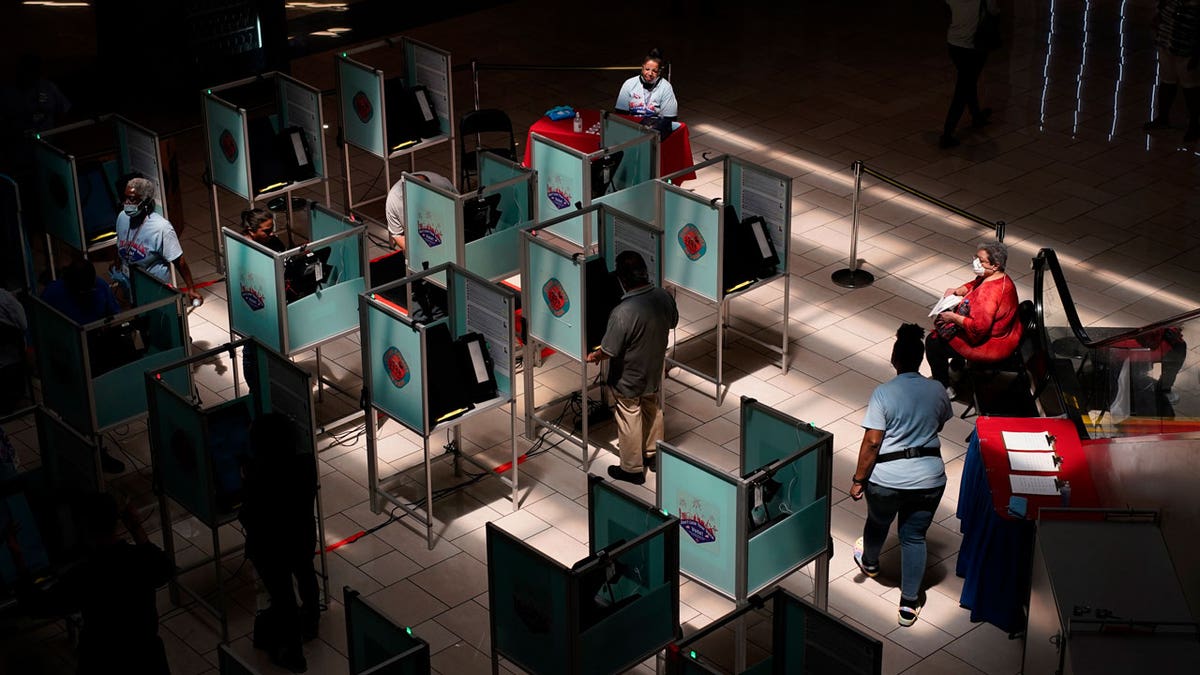 Election workers help as people vote at a polling place June 14, 2022, in Las Vegas.