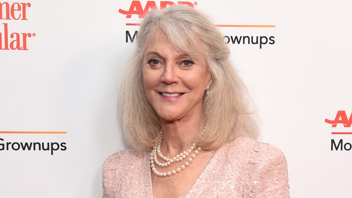 Blythe Danner smiles in a pink sparkly top with a chain pearl necklace