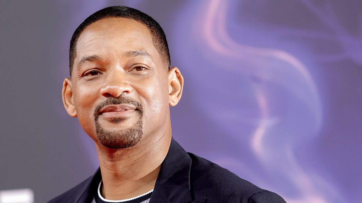 Will Smith looks off in the distance at the "Aladdin" premiere in Germany against a purple background