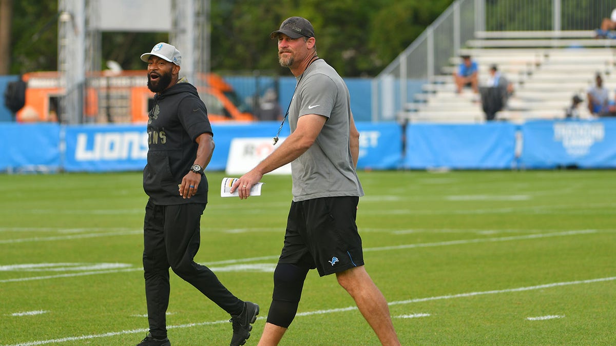 Dan Campbell and Aubrey Pleasant walk on the field during Lions training camp