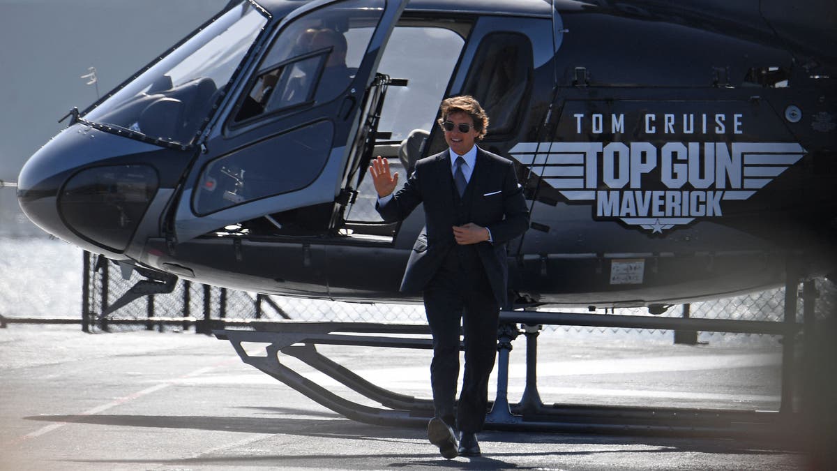 Tom Cruise step off a helicopter at the premiere of "Top Gun: Maverick" in a black suit