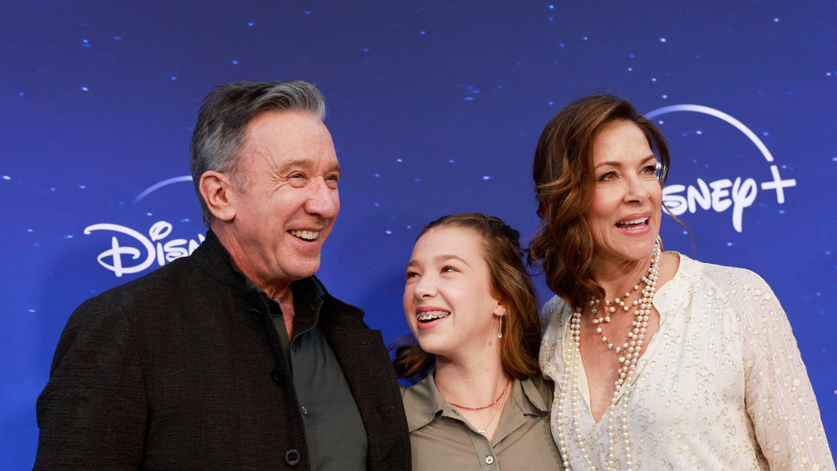 Tim Allen poses alongside his daughter Elizabeth Allen-Dick who looks up at him and smiles, alongside his wife Jane Hajduk