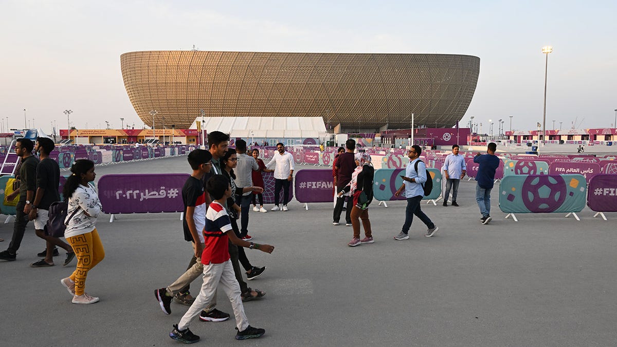 Fans walk past Lusail Stadium