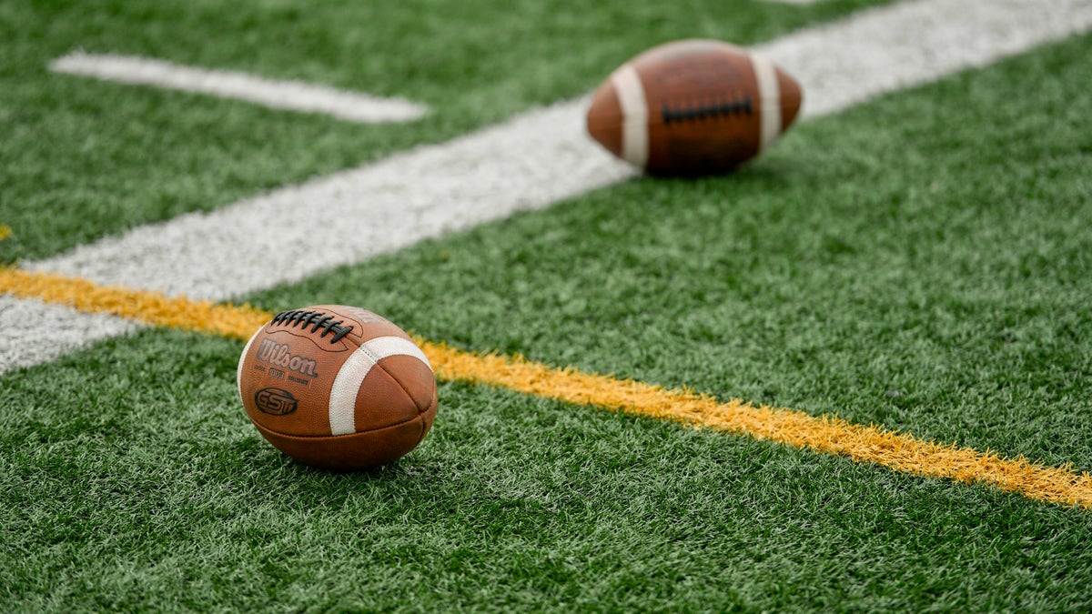 A picture of two footballs on a high school football field