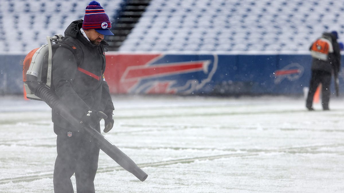 A field crew member tries to get snow off the Bills field