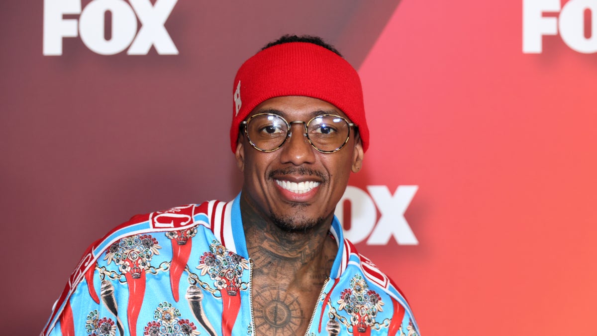 Nick Cannon smiles at the Fox Upfronts, in a red and blue shirt