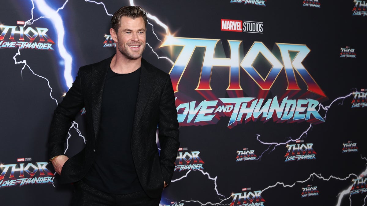 Chris Hemsworth smiles on the red carpet in an all black outfit for the "Thor: Love And Thunder" premiere in Australia