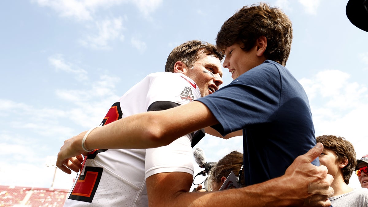 Tom Brady gives his son Jack Brady a hug at Raymond James stadium prior to the Buccaneer's game against the Packers