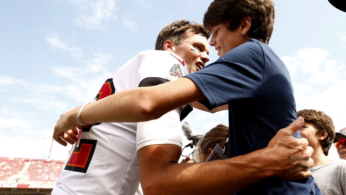 Tom Brady gives his son Jack Brady a hug at Raymond James stadium prior to the Buccaneer's game against the Packers