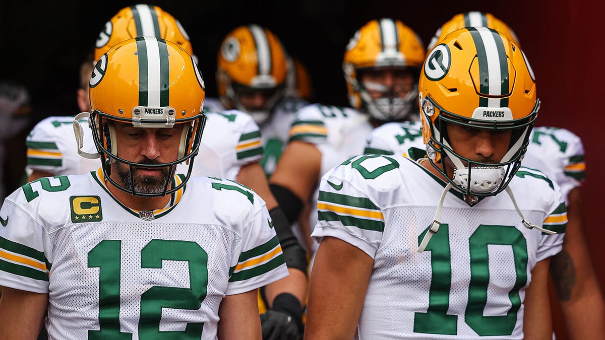 Aaron Rodgers and Jordan Love walk out on the field before a game against the Commanders