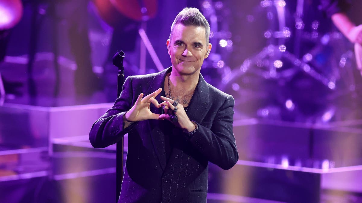 Robbie Williams makes a heart with his hands while on stage in Germany