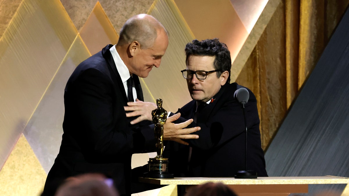 Woody Harrelson greets his friend Michael J. Fox on stage after presenting him with the Jean Hersholt Humanitarian Award