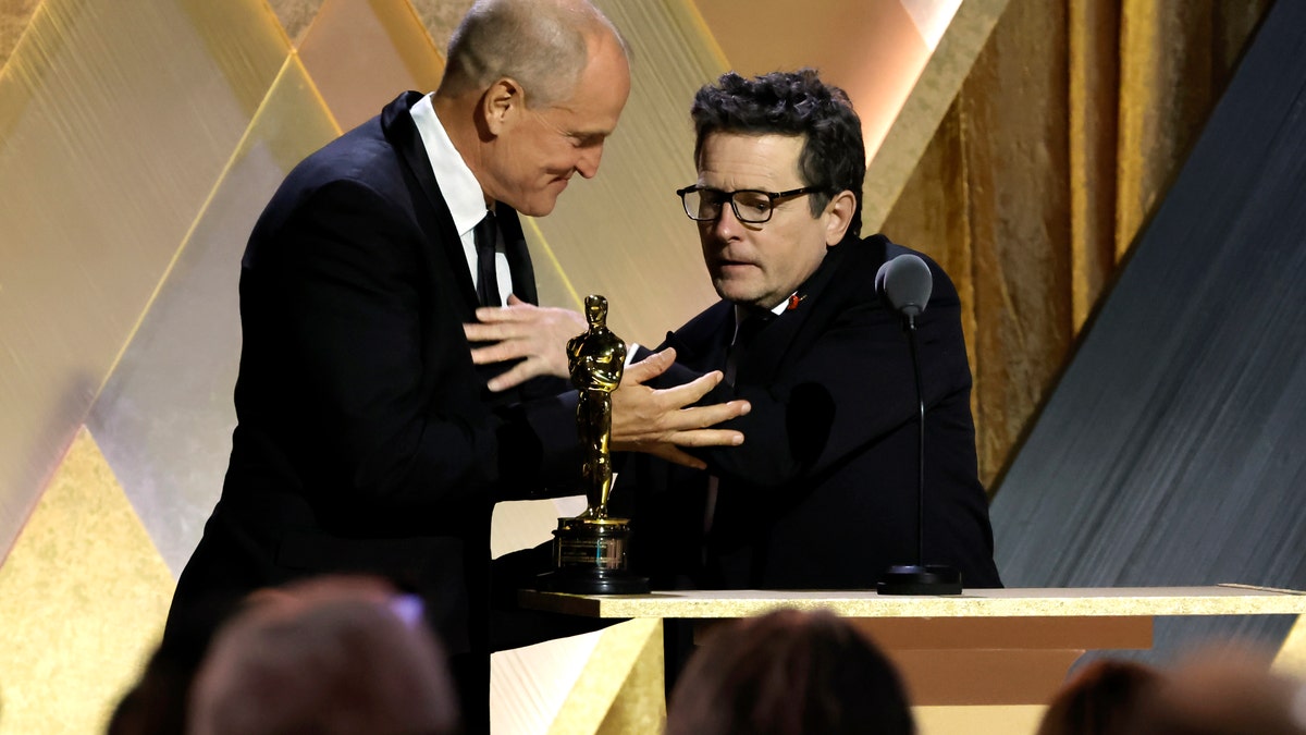 Woody Harrelson greets his friend Michael J. Fox on stage after presenting him with the Jean Hersholt Humanitarian Award