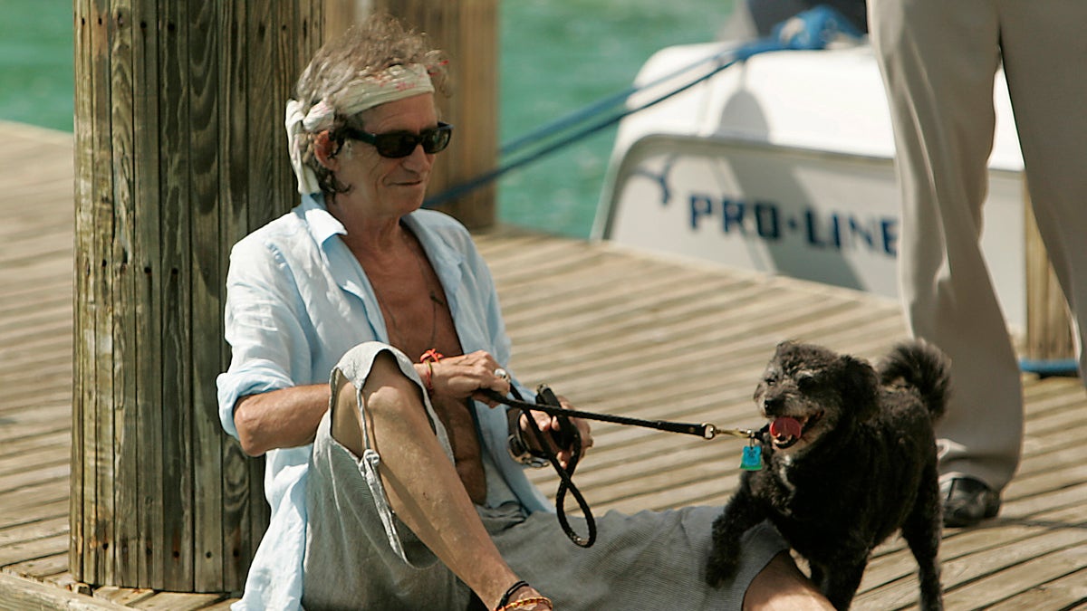 Rolling Stones guitarist Keith Richards lounges with his dog on a dock at Parrot Cay, a 1,000acre