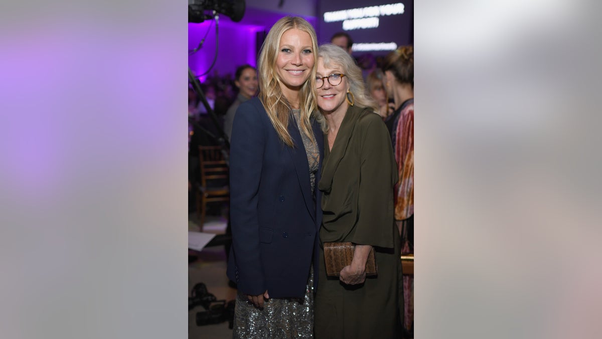 Gwyneth Paltrow in a blue suit and her mother Blythe Danner in an olive suit pose for a photo