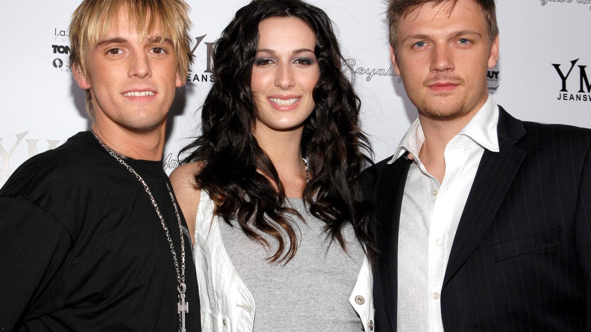 Aaron, Nick, and Angel Carter smile together on the red carpet