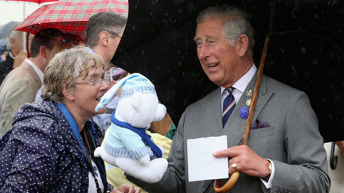 King Charles holding a teddy bear