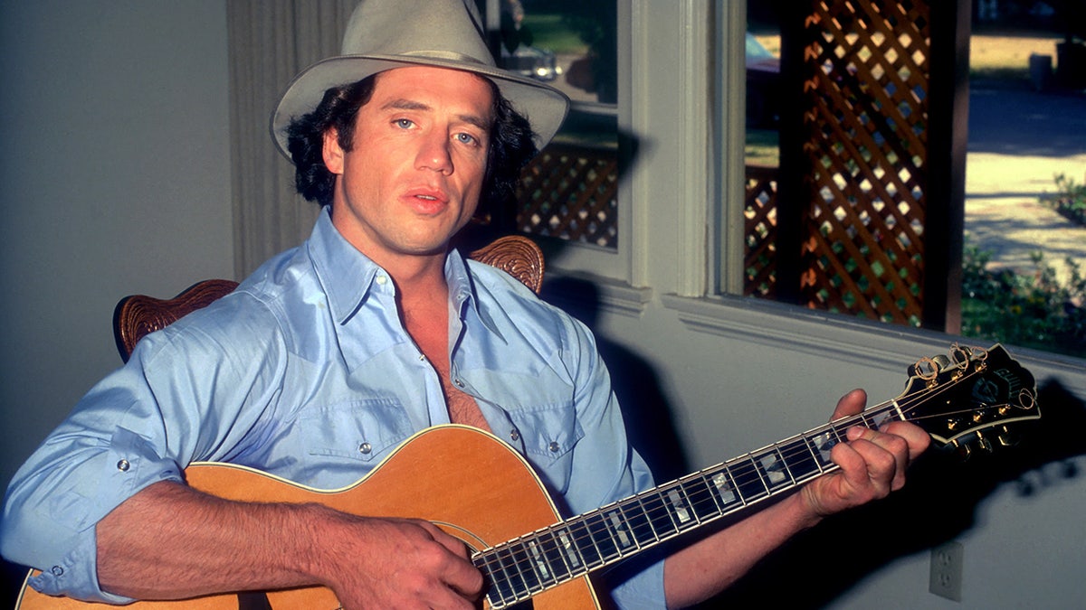 A young Tom Wopat playing guitar