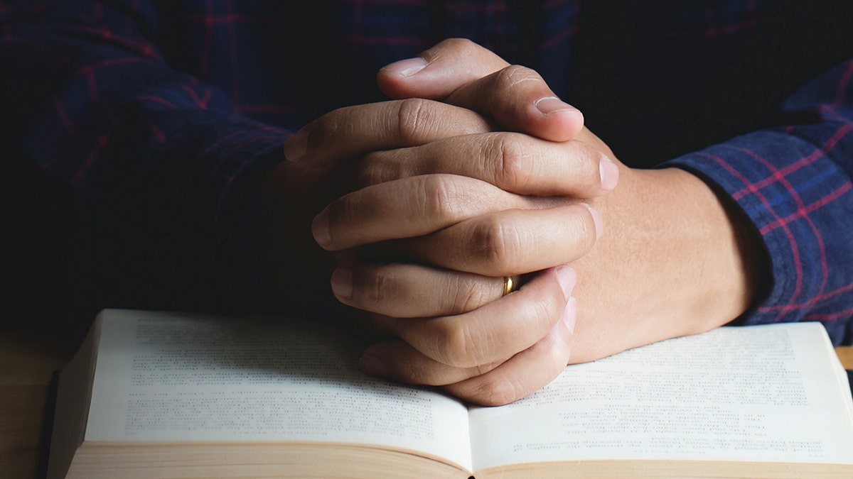 Man praying with hands in bible