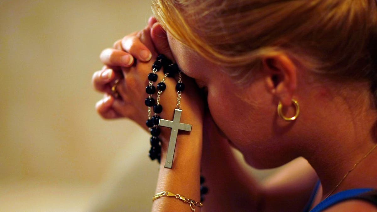 Woman praying with rosary