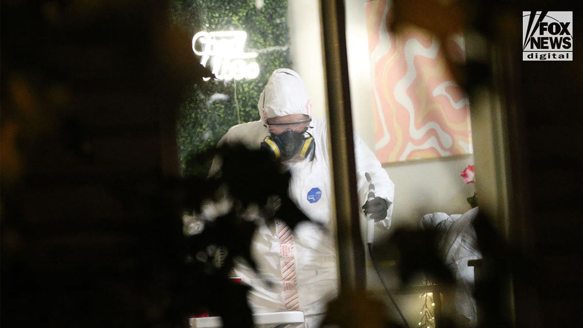 Investigator wearing a hazmat suit holding a device