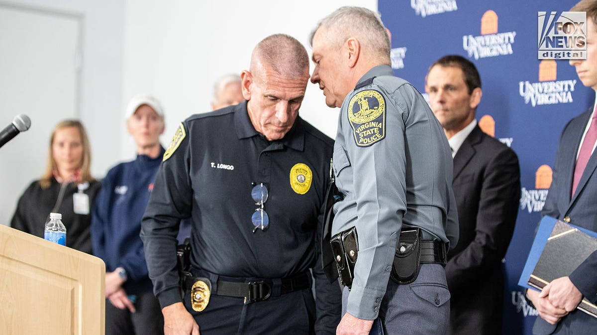 Police officers confer away from the podium