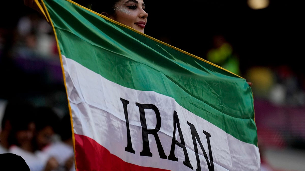 A soccer fan holds the Iran flag