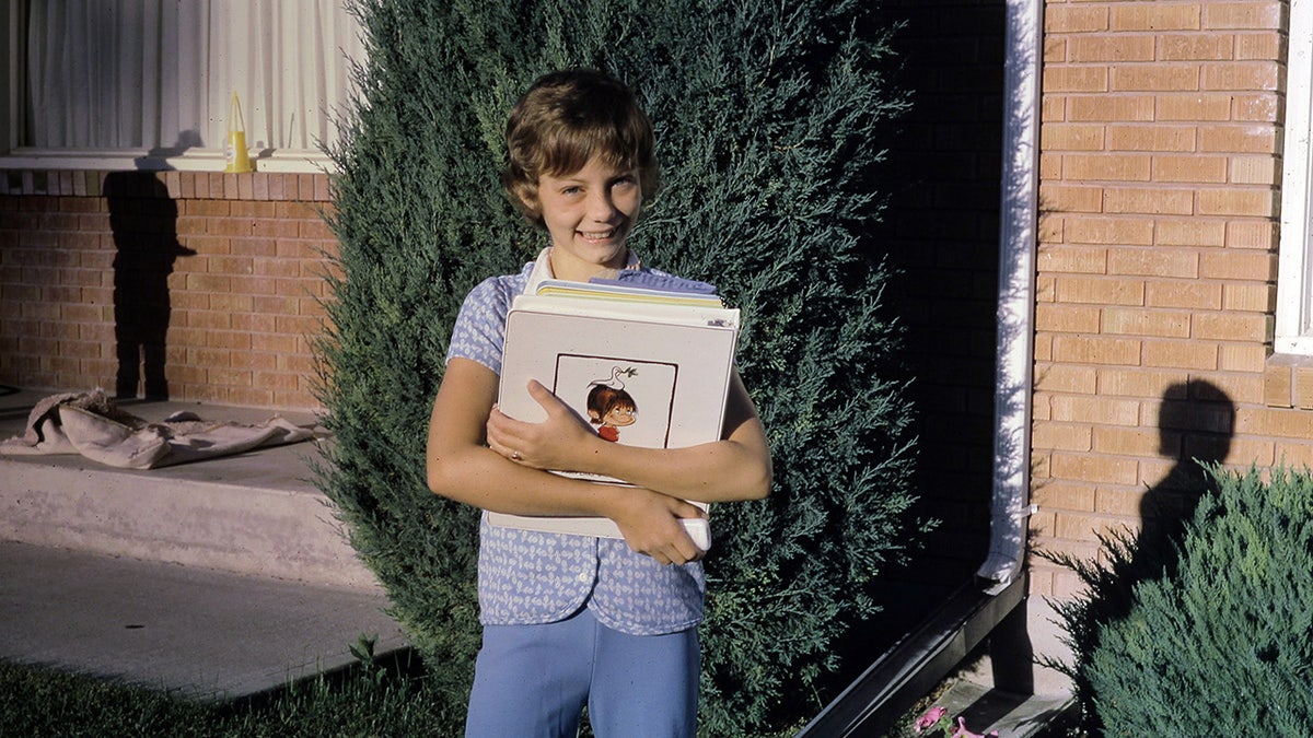 Jan Broberg as a child smiling while holding a book