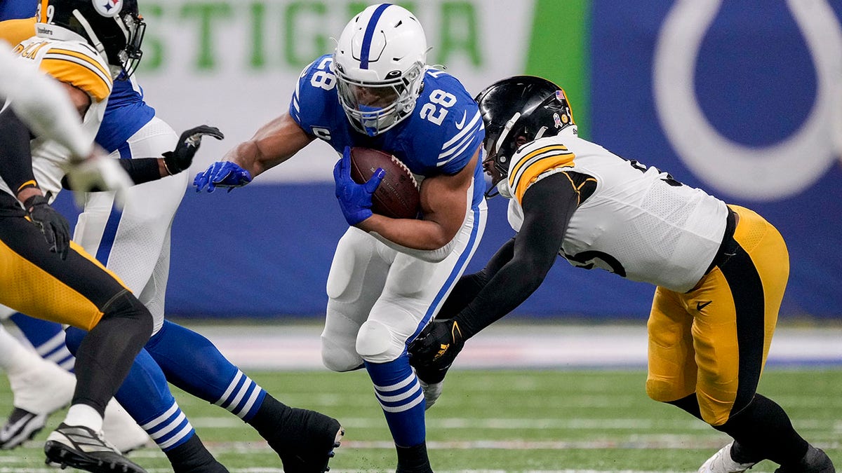 Nov 28, 2022; Indianapolis, Indiana, USA; Indianapolis Colts running back Jonathan Taylor (28) works to move past Pittsburgh Steelers inside linebacker Devin Bush (55) during the first half at Lucas Oil Stadium.