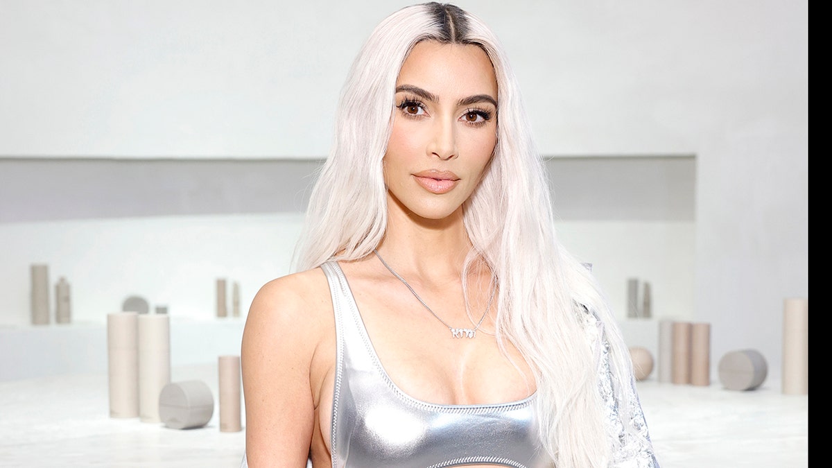 Kim Kardashian con el pelo rubio platino y vestida de plata mira directamente a la cámara